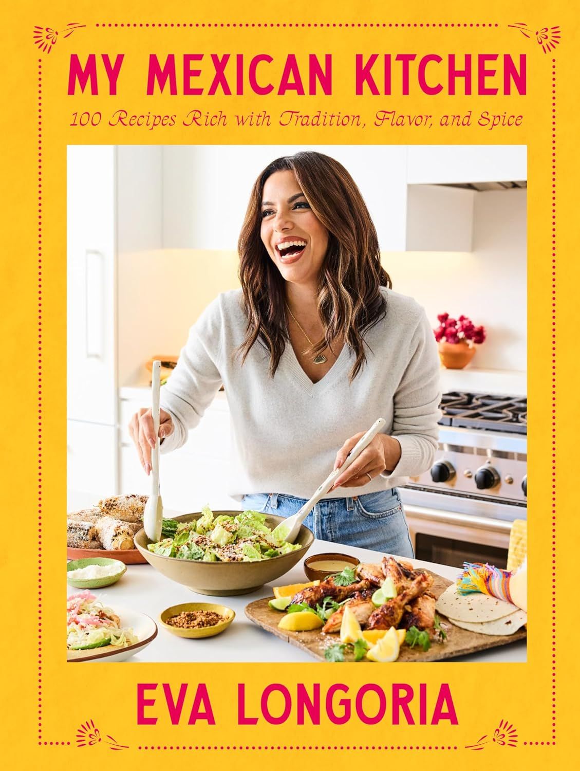 Cover of My Mexican Kitchen. Author Eva Longoria is standing in her kitchen, looking off-screen and laughing. She has serving spoons in her hands, like she's getting ready to place some of the salad in the bowl on a plate. There is more food in plates and bowls around her.