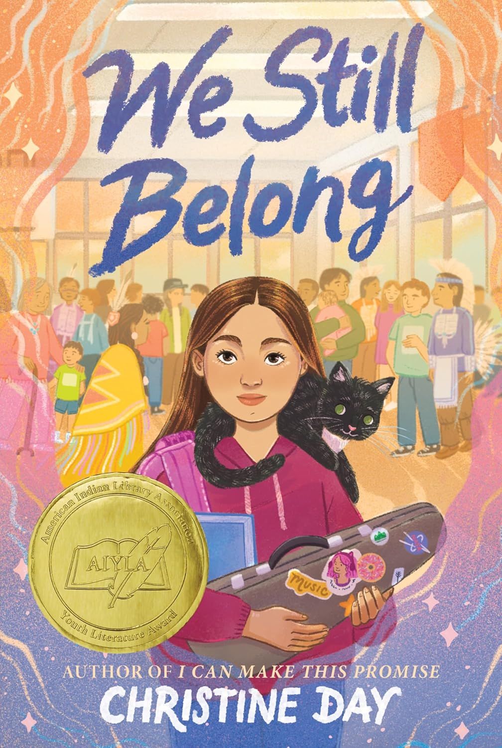 Cover of We Still Belong. Young woman with a black cat on her shoulder, holding a violin case with stickers on it, is in the foreground. Behind her are a crowd of people, some wearing traditional Native American clothes.