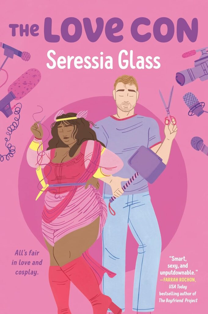 Cover of The Love Con. Pink background, with a darker pink circle in the lower center. The two main characters are posing in the center. The woman is wearing pink boots, and a light and dark pink costume with thread hanging off. The man is holding a pair of scissors in one hand, and a Thor hammer in the other. There are tv cameras and microphones surrounding them.
