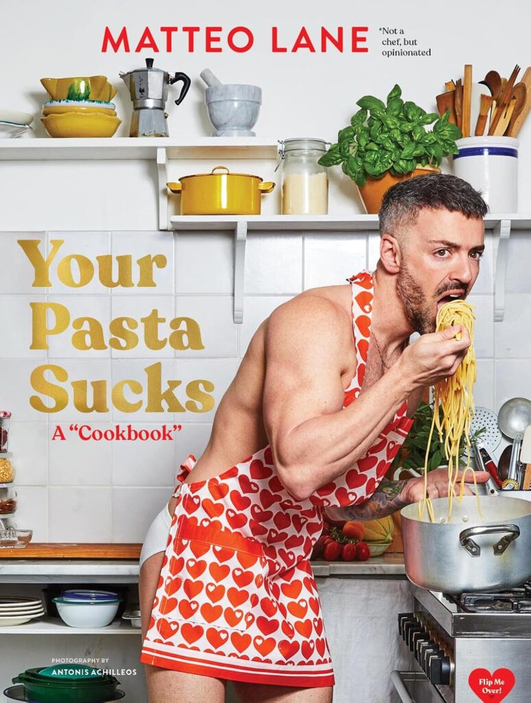 Cover of Your Pasta Sucks A "Cookbook." Author Matteo Lane is in underwear and a red heart apron, leaning over a pot with a giant spoonful of pasta almost at his mouth. There are dishes on open shelves behind him.