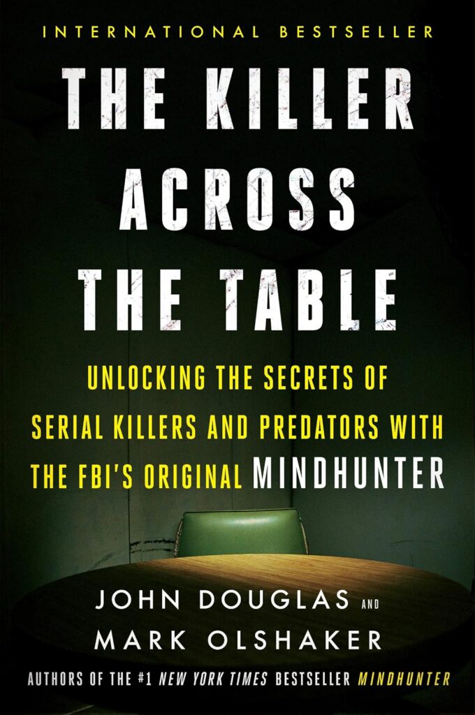 Cover of The Killer Across the Table: Unlocking the Secrets of Serial Killers and Predators with the FBI's Original Mindhunter. Photo of a green chair at a wood table; chair is lit while the rest of the room is dark.